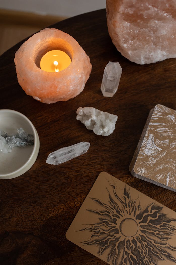 A serene top view of crystals, a candle, and esoteric cards on a wooden table.